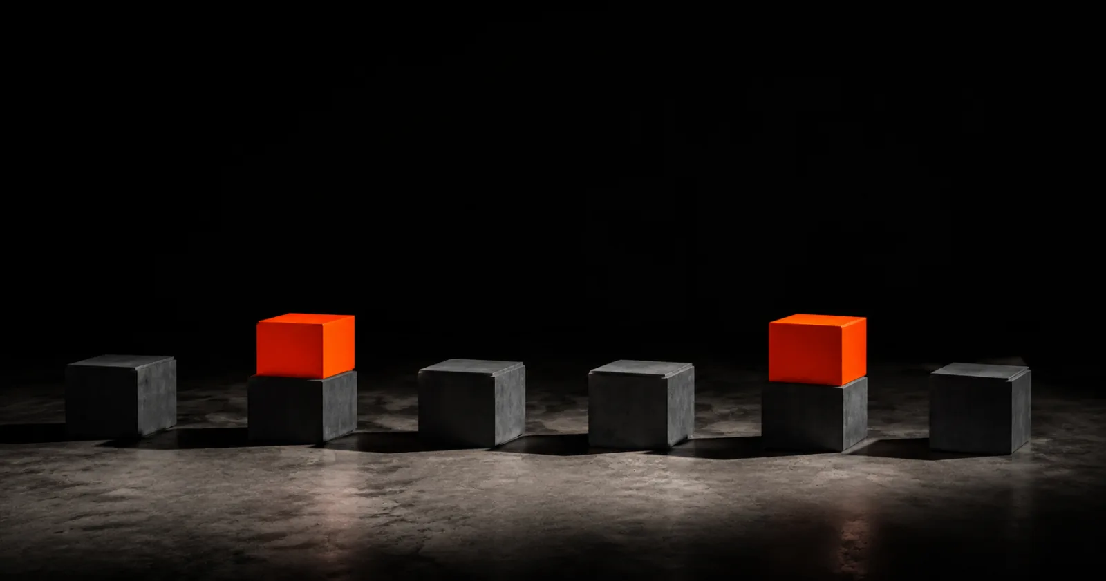 A row of concrete cubes where only two carry an orange block on top